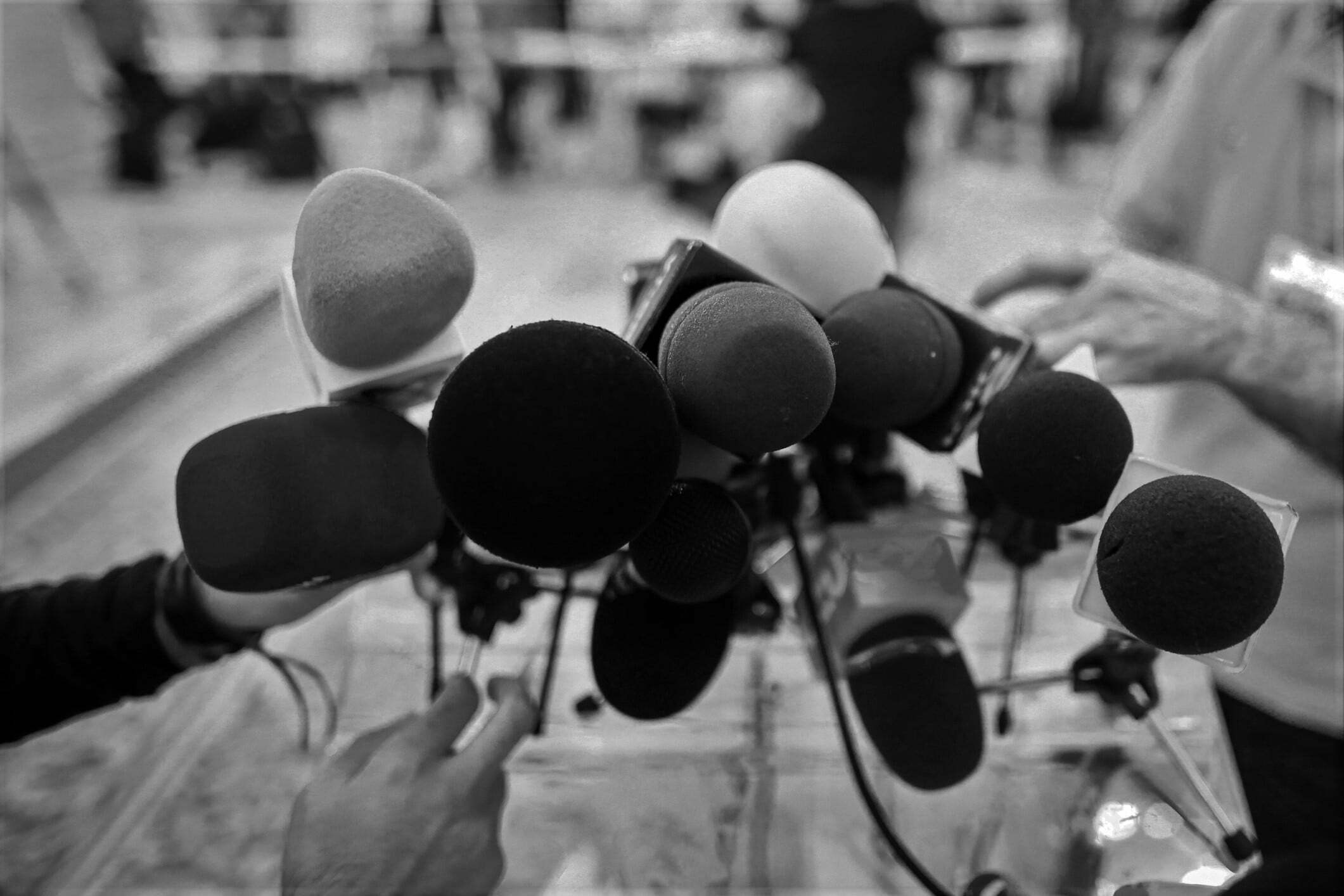 Shallow depth of field image with microphones installed by journalists at a press conference - politician point of view